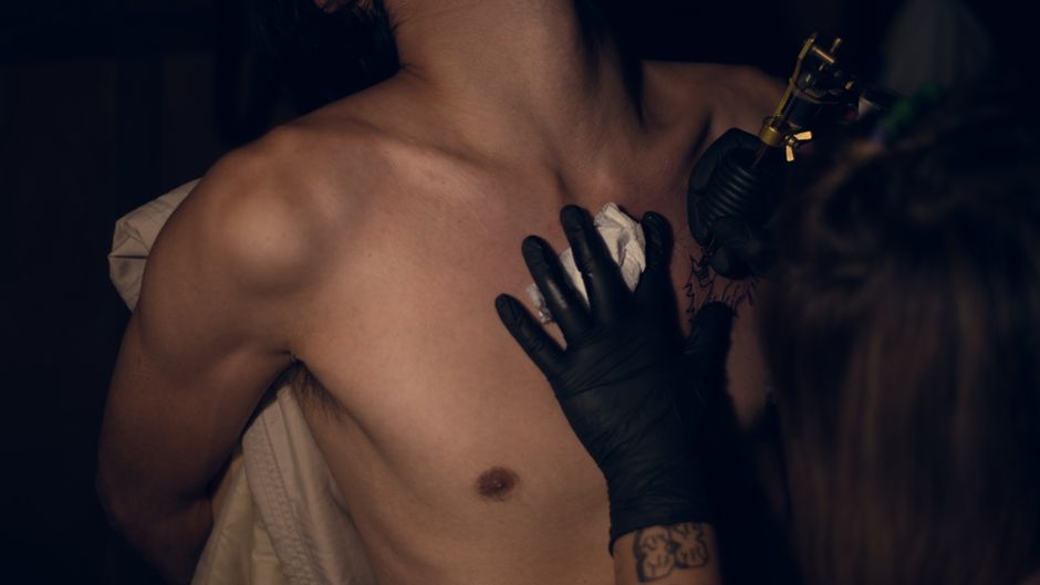 Interior de Blackline Studio, artista tatuando